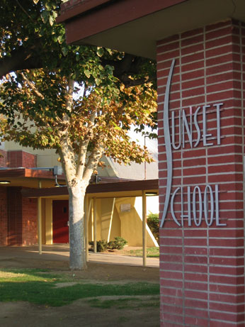 Sunset School logo on brick leading through to school court yard and tree at sunset